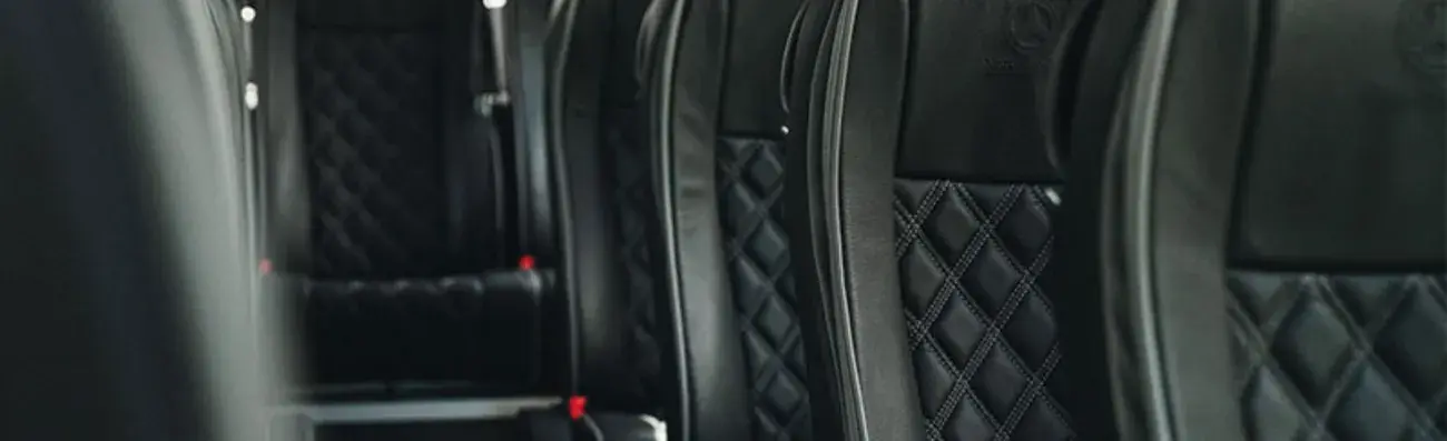 Luxury coach seats with black leather upholstery and diamond stitching.