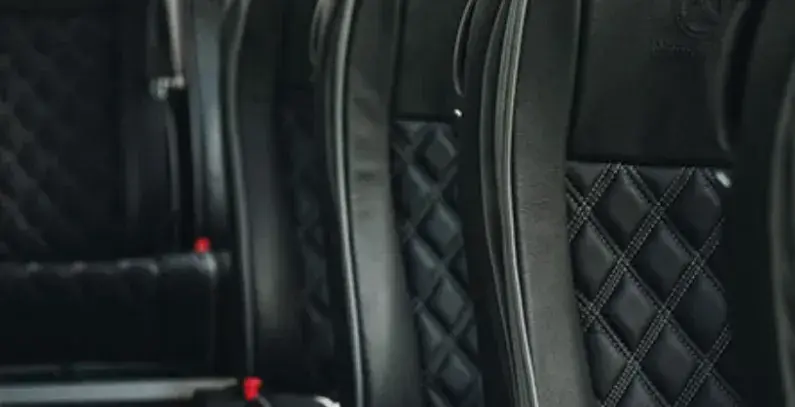 Luxury coach seats with black leather upholstery and diamond stitching.